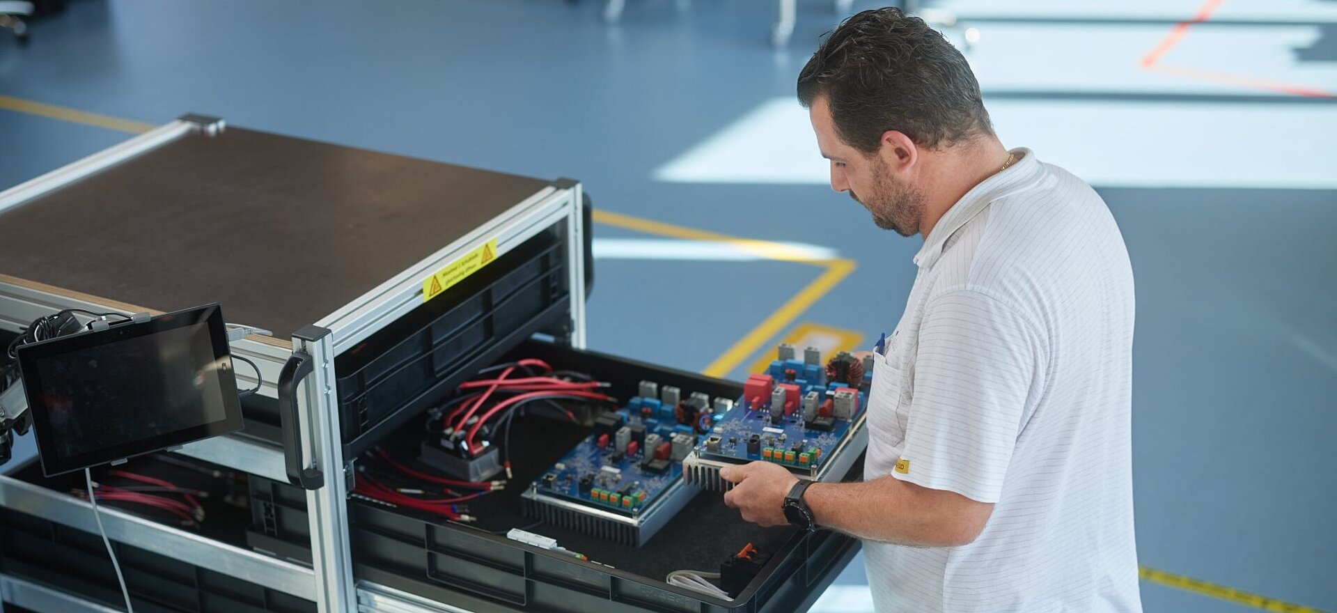 Mitarbeiter beim befüllen eines Schiebewagens mit elektronischen Bauteilen in der Produktion
