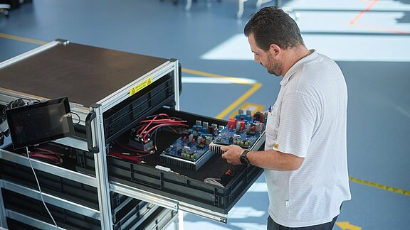 Employee filling a trolley with electronic components in production